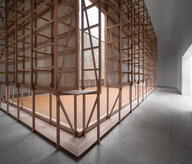 Beech wood skeleton clad in mycelium panels, aligned with the existing skylight, rammed earth floor.