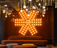 BeCentral espace collaboratif avec logo lumineux et plafond en tubes métalliques par l'architecte d'intérieur Maxime De Campenaere