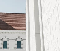 Vue extérieure du projet de réhabilitation Casterman par Atelier 2F. À côté d'une façade historique en briques restaurée se dresse une extension contemporaine épurée. Les nouveaux panneaux de béton architectonique, gravés de motifs évoquant des casses d'imprimerie, contrastent élégamment avec les textures de l'ancien bâtiment.
