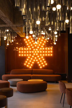 BeCentral espace collaboratif avec logo lumineux et plafond en tubes métalliques par l'architecte d'intérieur Maxime De Campenaere
